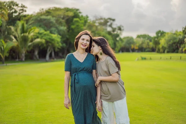 A heartwarming moment captured in the park as a pregnant woman after 40 shares a special bond with her teenage daughter, embracing the beauty of mother-daughter connection.