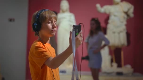 一个戴着面具的年轻人被描绘成正在参观历史博物馆 认真地听着音频向导 当他沉浸在镜头中时 摄像机捕捉了他好奇的表情和真正的兴趣 — 图库视频影像