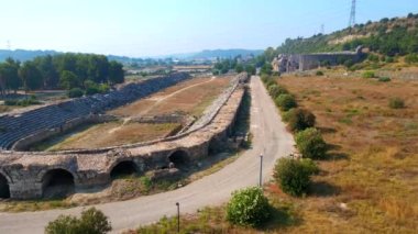 Hava videosu. İnsansız hava aracı, Türkiye 'nin Antalya kentindeki antik Perge kentinin kalıntılarında hipodromun üzerinde uçuyor. Hipodrom, geçmişin canlı yaşamının bir göstergesidir.