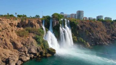 Antalya şehrindeki Lower Duden Şelalesi 'nin yavaş çekim videosu. İHA geriye doğru hareket ediyor. Çevredeki parkları ve binaları gösteriyor..