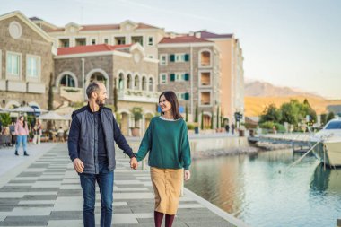 Karadağ 'ın Lustica Körfezi' ndeki mimari ve lüks yatların manzarasının keyfini çıkaran aşık turist çiftler. Karadağ 'da seyahat etmek. Her yere git..