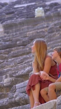 Dikey video. Hikaye biçimi. Bu anımsatıcı stok videosunda, antik Aspendos şehri turist bir ailenin varlığıyla canlanıyor. Kamera büyüleyici bir harabenin kalıntılarını yakalıyor.