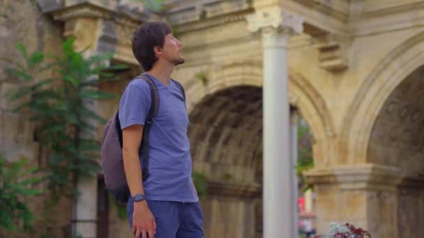 この魅惑的なビデオでは 若い男性の観光客がアンタルヤの有名な観光名所 ハドリアンズゲートを訪問して描かれています 彼は壮大なアーチウェイの前に立って 複雑に飾られています — ストック動画