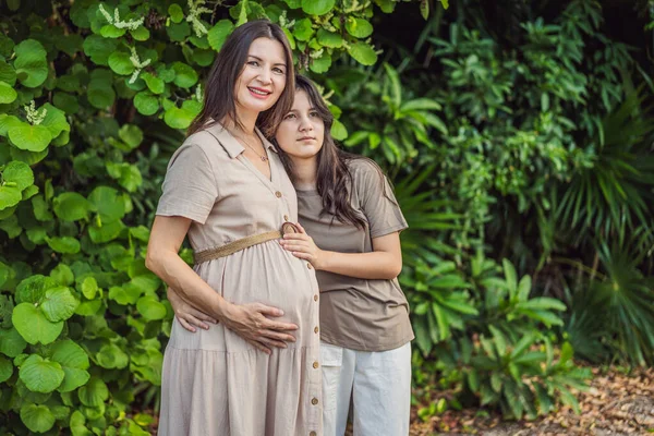A heartwarming moment captured in the park as a pregnant woman after 40 shares a special bond with her teenage daughter, embracing the beauty of mother-daughter connection.