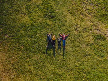 Aile manzarası. Çimlerin üzerinde yatıyordu. Güneşli bir gün. Yeşil doğada birlikte. Hava görüntüleme Drone fotoğrafçılığı.