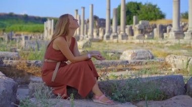 Türkiye 'nin Antalya kentindeki antik Perge kentinin olağanüstü kalıntılarını ziyaret eden genç bir kadın görülüyor. Harabeler, şehrin zengin geçmişinin bir kanıtı olarak duruyor. Sokakların kalıntılarıyla birlikte.