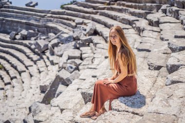 Kadın turist, Antik Termessos Şehrinin Çarpıcı Antik Tiyatrosunu keşfediyor. Hindi, her yere git.