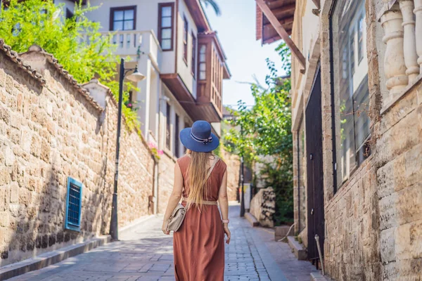 Antalya 'nın arka planındaki mutlu kadın turist. Kadın turist ilginç yerler ve popüler yerler keşfediyor ve Türkiye 'nin Antalya kentindeki eski Kalechi kentinde yürüyor. Türkiye.