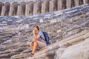 Erkek turist Aspendo Antik Şehir 'i keşfediyor. Aspendos akropolis şehir kalıntıları, sarnıçlar, su kemerleri ve eski tapınaklar. Aspendos Antalya hindisi. Türkiye.