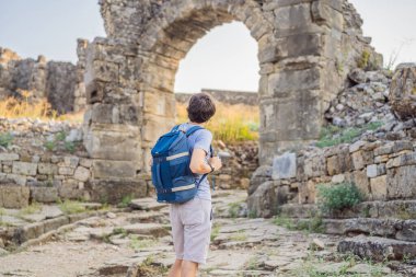 Erkek turist Aspendo Antik Şehir 'i keşfediyor. Aspendos akropolis şehir kalıntıları, sarnıçlar, su kemerleri ve eski tapınaklar. Aspendos Antalya hindisi. Türkiye.
