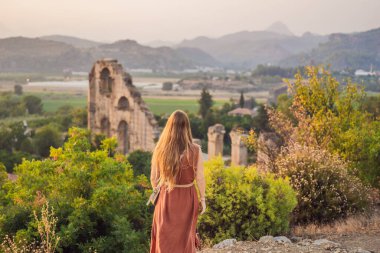Kadın turist Aspendos Antik Şehri 'ni keşfediyor. Aspendos akropolis şehir kalıntıları, sarnıçlar, su kemerleri ve eski tapınaklar. Aspendos Antalya hindisi. Türkiye.
