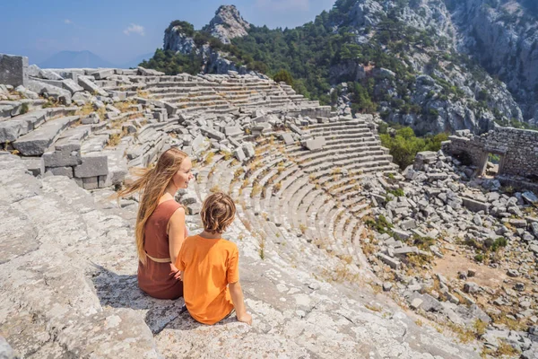 mother and son tourists explores Stunning Ancient Theater of Termessos Ancient City. Traveling with kids concept. turkiye, GO Everywhere.