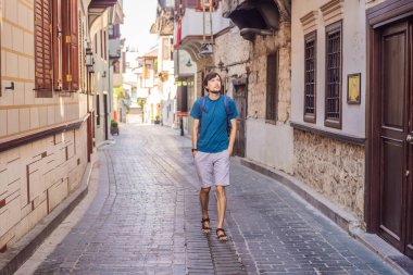 Antalya 'nın arka planındaki mutlu turist. Erkek turist ilginç yerler ve popüler yerler keşfediyor ve Türkiye 'nin Antalya kentindeki eski Kalechi kentinde yürüyor. Türkiye.