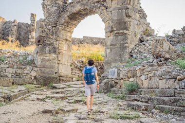 Erkek turist Aspendo Antik Şehir 'i keşfediyor. Aspendos akropolis şehir kalıntıları, sarnıçlar, su kemerleri ve eski tapınaklar. Aspendos Antalya hindisi. Türkiye.