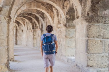 Erkek turist Aspendo Antik Şehir 'i keşfediyor. Aspendos akropolis şehir kalıntıları, sarnıçlar, su kemerleri ve eski tapınaklar. Aspendos Antalya hindisi. Türkiye.