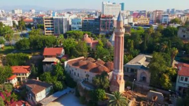 Gökyüzü stok videosu, ikonik Yivli Minare Camii Antalyas tarihi merkezi Türkiye 'nin göbeğinde yer alıyor. Kamera zarif bir şekilde yukarıda süzülüyor, bunun panoramik bir görüntüsünü sunuyor.