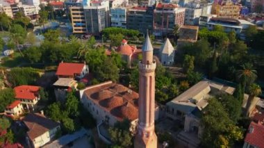 Gökyüzü stok videosu, ikonik Yivli Minare Camii Antalyas tarihi merkezi Türkiye 'nin göbeğinde yer alıyor. Kamera zarif bir şekilde yukarıda süzülüyor, bunun panoramik bir görüntüsünü sunuyor.