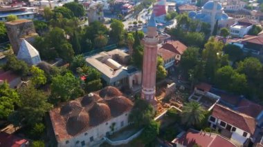 Gökyüzü stok videosu, ikonik Yivli Minare Camii Antalyas tarihi merkezi Türkiye 'nin göbeğinde yer alıyor. Kamera zarif bir şekilde yukarıda süzülüyor, bunun panoramik bir görüntüsünü sunuyor.