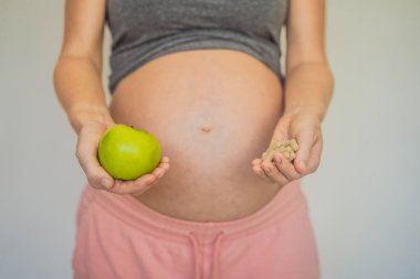 Düşünceli bir an: Hamile bir kadın, beslenme ihtiyaçları için doğal meyve ya da takviyeler arasında, doğa ve bilim arasında bir seçim yapmayı düşünür..