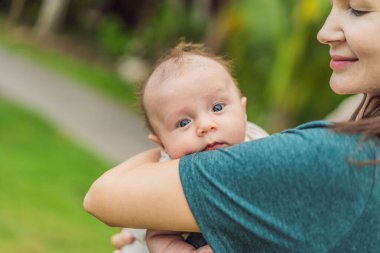 40 yaşında mutlu bir anne, yeni doğan bebeğini güneşli bir parkta beşikte tutuyor. Aşk, aile ve nesiller uyum içinde..