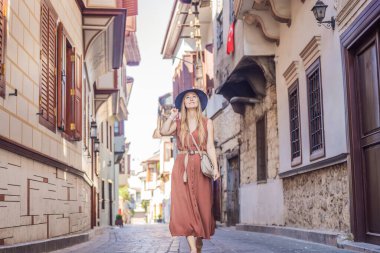 Antalya 'nın arka planındaki mutlu kadın turist. Kadın turist ilginç yerler ve popüler yerler keşfediyor ve Türkiye 'nin Antalya kentindeki eski Kalechi kentinde yürüyor. Türkiye.