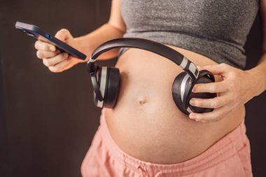 Rahimdeki melodiler: hamile bir karnına yerleştirilmiş kulaklıklar, müzikle bağlanma, anne ve bebek arasında yürek ısıtan bir bağ.