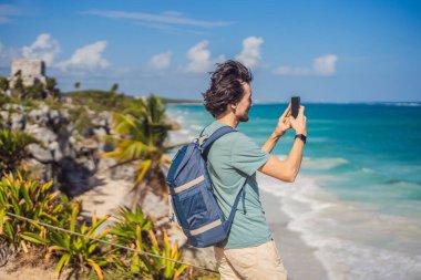 Erkek turist, Kolombiya öncesi Maya şehri Tulum, Quintana Roo, Meksika, Kuzey Amerika, Tulum, Meksika 'nın manzarasını seyrediyor. El Castillo - Şato Maya şehri Tulum ana tapınağı.