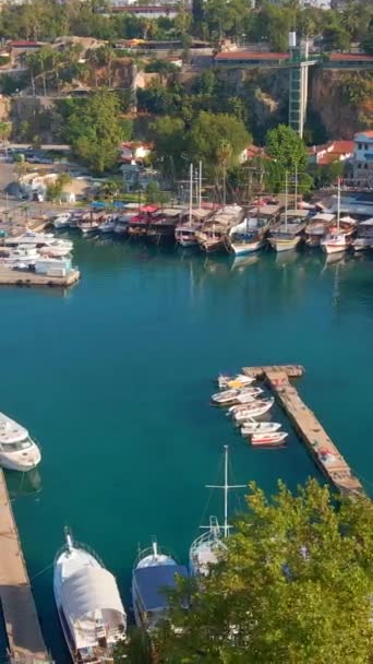 この空中ストックビデオでは アンタルヤの古い港の絶え間ない美しさが現れます カメラはトルコのアンタルヤの古い町に囲まれた歴史的な港の上に現れます シーンショーケース — ストック動画