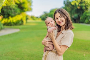 40 yaşında mutlu bir anne, yeni doğan bebeğini güneşli bir parkta beşikte tutuyor. Aşk, aile ve nesiller uyum içinde..