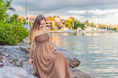 Hamile bir kadın dışarıda karnına sarılıyor. Doğayla iç içe. Hamilelik, beklenti, annelik kavramı..