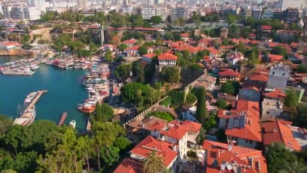 この空中ストックビデオでは アンタルヤの古い港の絶え間ない美しさが現れます カメラはトルコのアンタルヤの古い町に囲まれた歴史的な港の上に現れます シーンショーケース — ストック動画