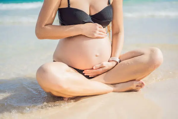 Expectant mother finds inner calm through meditation by the tranquil turquoise sea. A serene moment of pregnancy and peace.