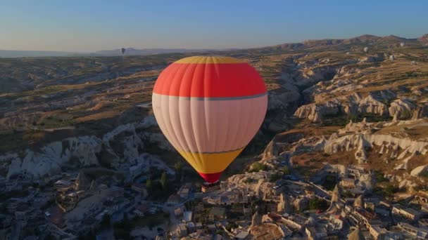 この空中ビデオでは トルコのカッパドキアの上空は 熱気球のケルドスコープで生きています 地域の象徴的な谷 フィールドの背景に対して この魅惑的な — ストック動画
