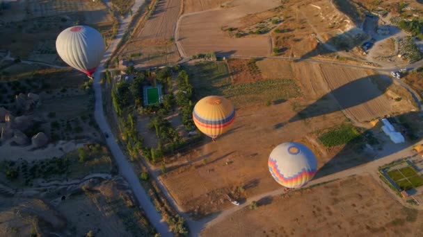 この空中ビデオでは トルコのカッパドキアの上空は 熱気球のケルドスコープで生きています 地域の象徴的な谷 フィールドの背景に対して この魅惑的な — ストック動画