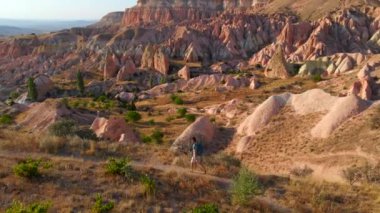 Kapadokya, Goreme yakınlarındaki Kızıl ya da Pembe Vadi 'de bir turist ailesi yürüyüş yapıyor. Sıcak tonlarda boyanmış manzara eşsiz jeolojik oluşumları ve peri bacalarını gözler önüne seriyor.