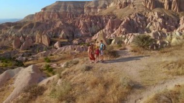 Kapadokya, Goreme yakınlarındaki Kızıl ya da Pembe Vadi 'de bir turist ailesi yürüyüş yapıyor. Sıcak tonlarda boyanmış manzara eşsiz jeolojik oluşumları ve peri bacalarını gözler önüne seriyor.
