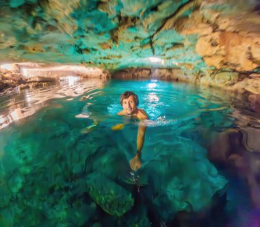 Man immersed in the enchanting beauty of a Mexican cenote, surrounded by crystal-clear waters and captivating natural formations. clipart