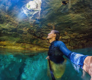 Meksika mezarlığının büyüleyici güzelliğine dalmış bir adam, kristal berrak sular ve büyüleyici doğal oluşumlarla çevrili..