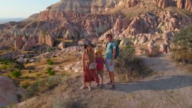 Kapadokya, Goreme yakınlarındaki Kızıl ya da Pembe Vadi 'de bir turist ailesi yürüyüş yapıyor. Sıcak tonlarda boyanmış manzara eşsiz jeolojik oluşumları ve peri bacalarını gözler önüne seriyor.