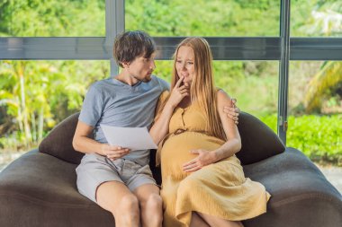 Hamilelik ve Aile Bütçesi Konsepti. Genç çift bebek bekliyor, bütçe planlıyorlar ve evde para sayıyorlar..