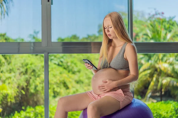 A pregnant woman utilizes a pregnancy app or contraction counter, harnessing technology to monitor and track her pregnancy journey and contractions.