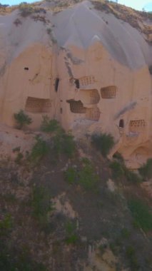 Dikey video. Türkiye 'nin Goreme kenti yakınlarındaki Cappadocias mağara evlerinin özünü yakalayan bu büyüleyici havacılık videosuyla görsel bir yolculuğa çıkın. Kuşbakışı perspektif açılır