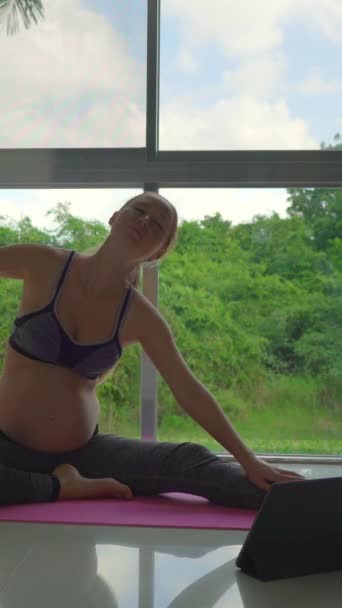在她的公寓里 可以看到年轻的孕妇在做瑜伽练习 背景是全景窗和茂密的热带背景 缓慢而优雅的动作 — 图库视频影像