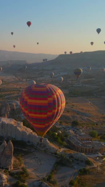 バーティカルビデオ この空中ビデオでは トルコのカッパドキアの上空は 熱気球のケルドスコープで生きています 地域の象徴的な谷 フィールドの背景に対して — ストック動画