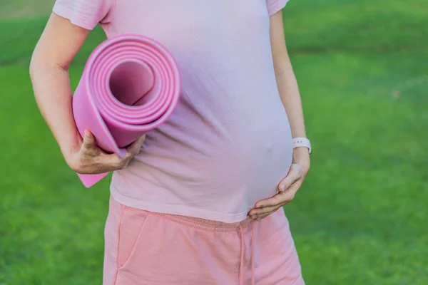 エネルギッシュな妊娠中の女性は 爽快で健康に配慮した屋外運動セッションのために運動マットを使用して 屋外で彼女のトレーニングを取ります — ストック写真