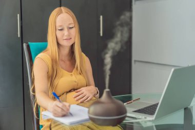 Beklenen kadın, hamilelik sırasında rahatlatıcı bir atmosfer için koku yayıcı kullanarak iş ortamını geliştiriyor..