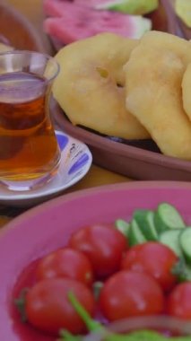 Dikey video. Geleneksel Türk kahvaltısının canlı duvar halısının keyfini bu yakın çekim videoyla çıkarın. Taze sebzelerden krem peynirlere, sıcak ekmeklere ve çırpılmış yumurtalara.