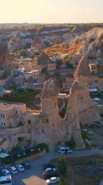 Dikey video. Goreme 'in hava görüntüleri, Kapadokya, Türkiye. Aşağıdaki antik şehir, kayalara güzelce oyulmuş evlerle olağanüstü çekiciliğini gözler önüne seriyor. Eşsiz kaya oluşumları