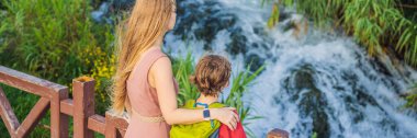 Banner, eski anne ve oğul turistler, Antalya 'daki Duden şelalesinin arka planında. Türkiye 'nin ünlü yerleri. Duden Şelalesi 'nin aşağısında kayalık bir uçurum 40 metreden aşağı düşüyor.