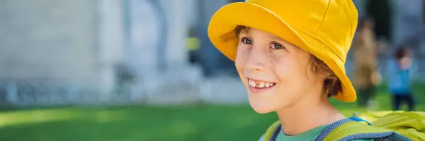 Smiling toothless boy of seven years old, sits outdoors in the summer. BANNER, LONG FORMAT